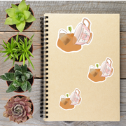 a spiral-bound notebook with various potted plants and a cup of tea on a wooden surface.
