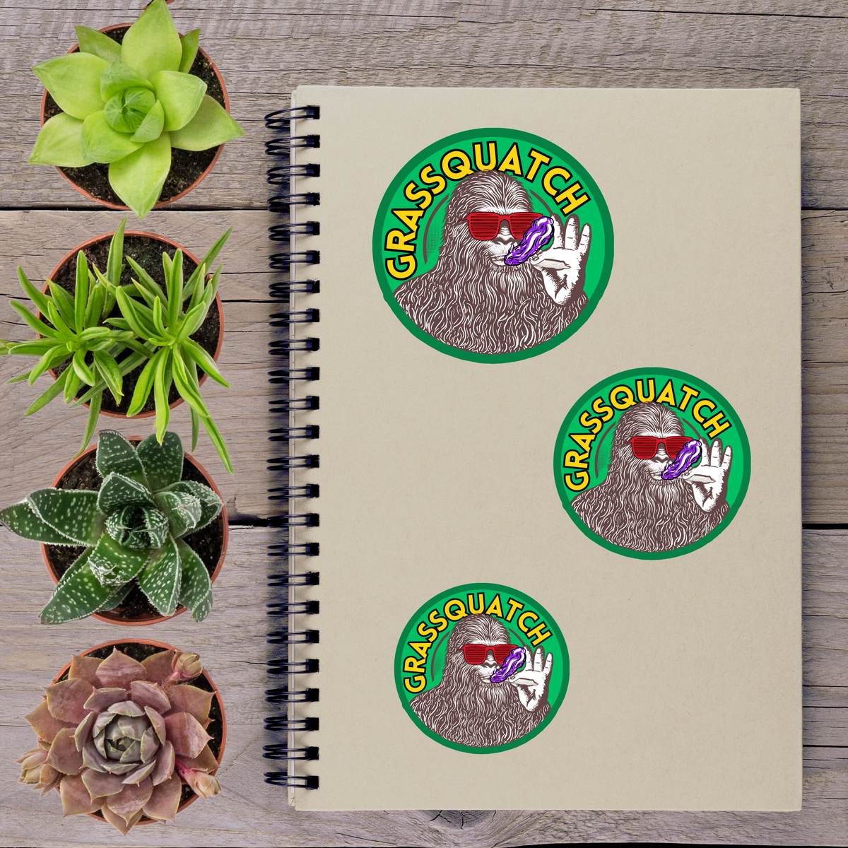 a spiral notebook with stickers on it, surrounded by various potted plants.