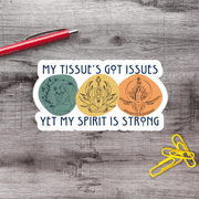 A sticker with the text "MY TISSUE'S GOT ISSUES YET MY SPIRIT IS STRONG" and three circular illustrations, one of which is a person in a meditative pose.