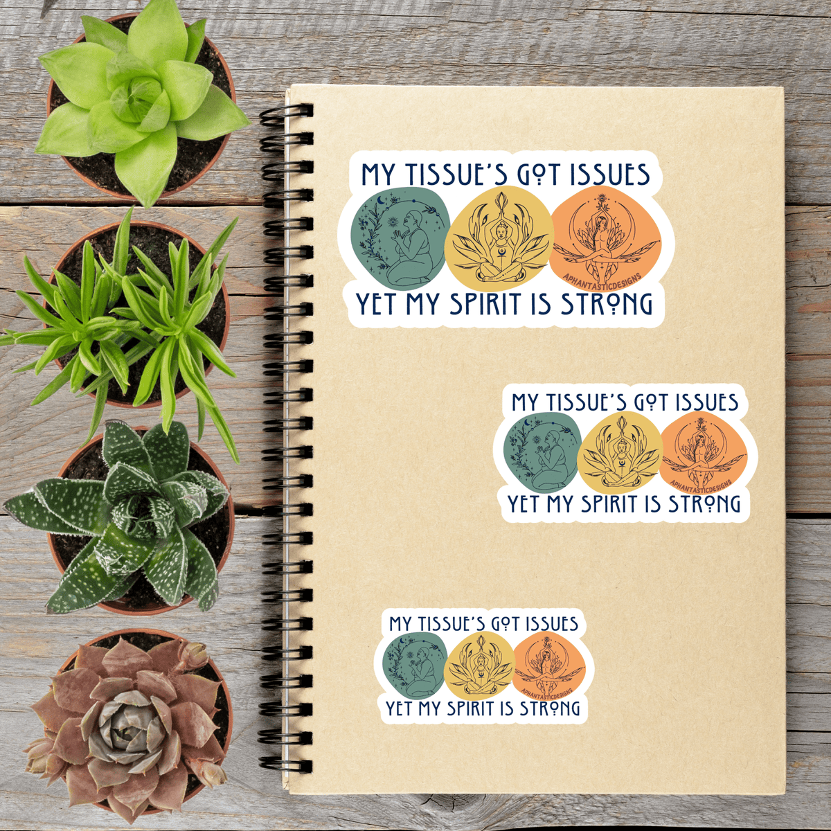 a notebook with stickers on it, along with four potted succulent plants arranged on a wooden surface.