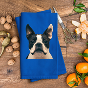 A blue towel with a picture of a dog is placed on a wooden surface, surrounded by various fruits such as oranges and walnuts.